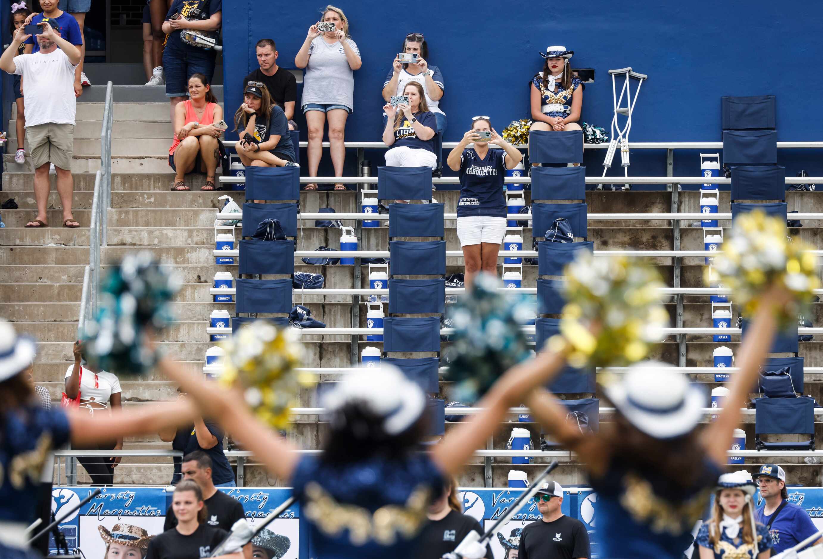 Crowds watch as McKinney Marquettes team performs after a season-opening football game...