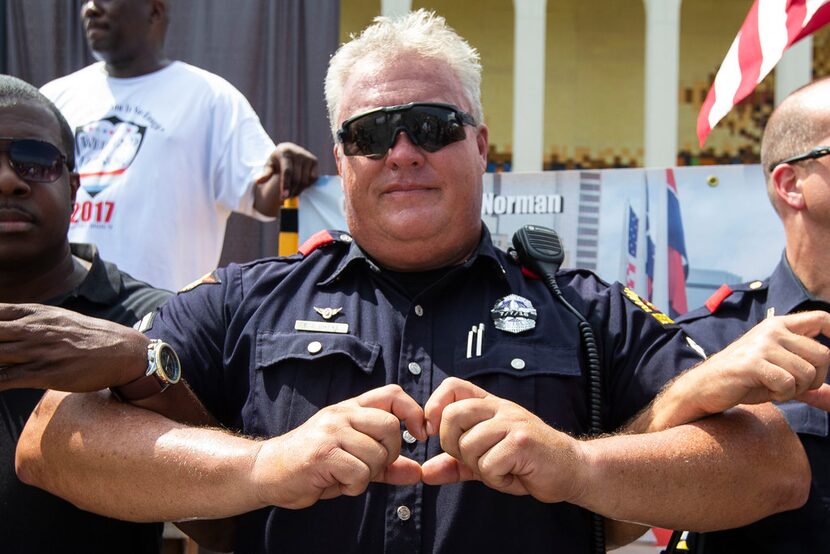 Dallas Police motorcycle officer Earl "Jamie" Givens and others hold their hands in the...