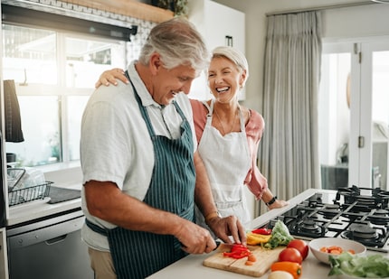 Senior couple, cooking and having fun while preparing a healthy food with vegetables for a...