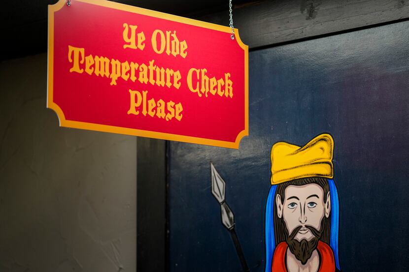 A sign marks a temperature check point for guests entering Medieval Times in Dallas.