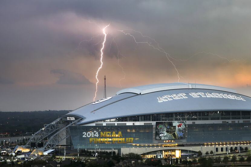 A lightning bolts strike from a passing thunderstorm in S. Arlington behind AT&T Stadium in...