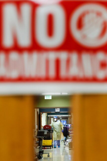 A health care worker is seen through a doorway in the COVID-19 Tactical Care Unit at...