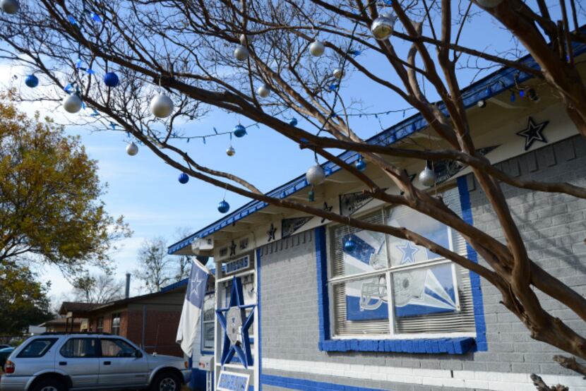 Silver and blue Christmas balls hang on a tree outside the Cowboys house at the corner of...