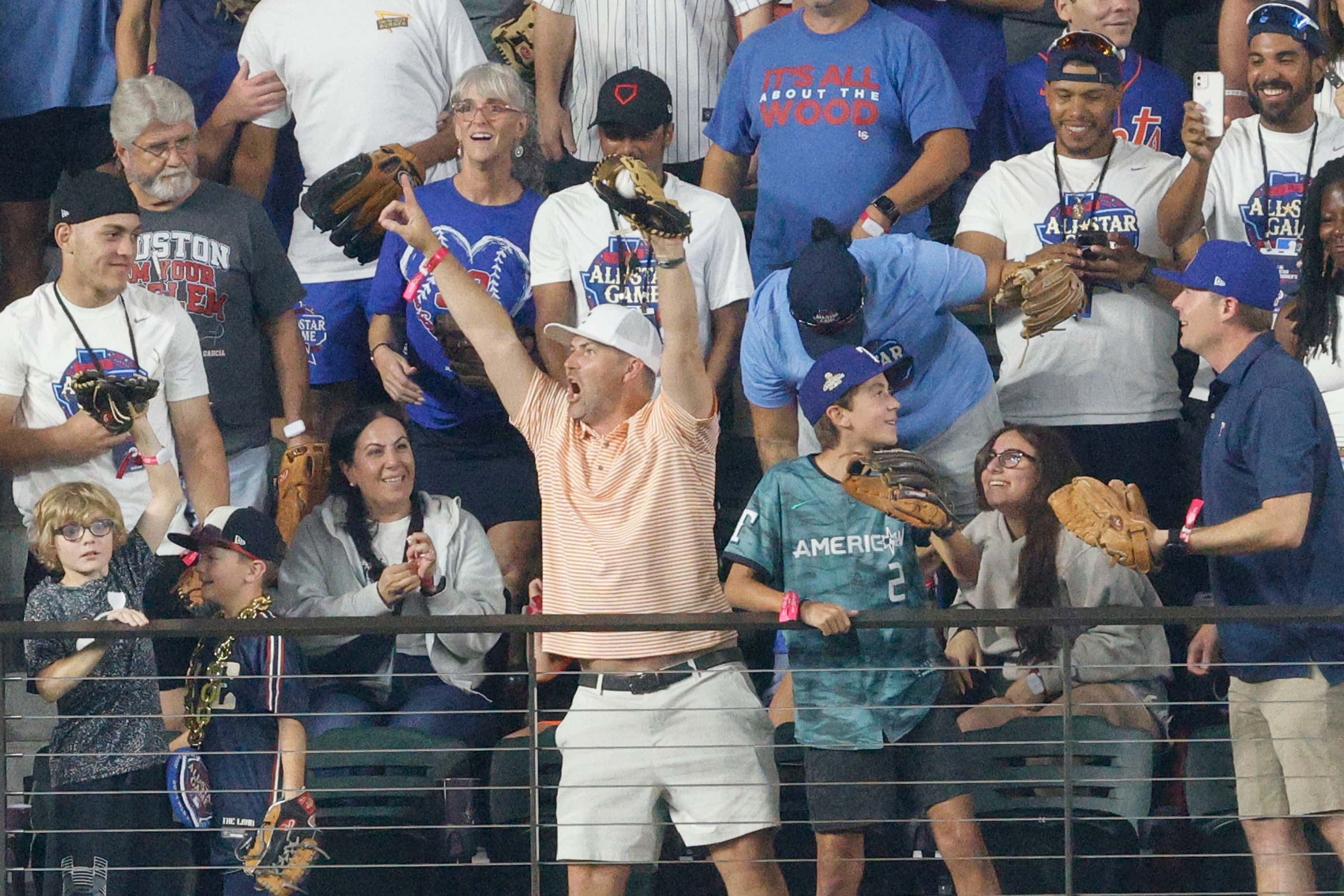 A fan reacts after he caught a ball hit by American League's Adolis Garcia, of the Texas...