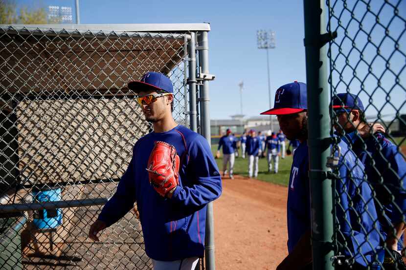 Texas Rangers pitcher Yu Darvish walks out to a field to stretch during a workout at the...