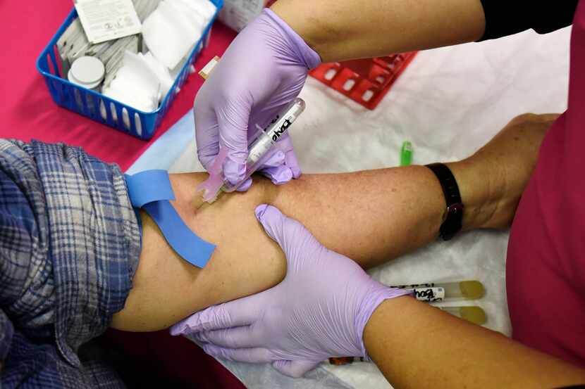 Sherry Boyd, 60, left, has her blood collected for free lab tests during a health and safety...