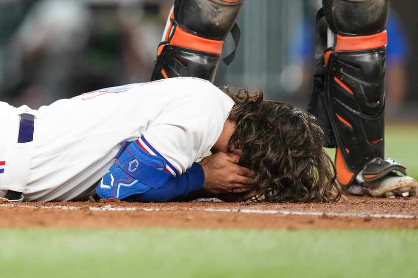 Texas Rangers outfielder Josh Smith lies on the ground after he was hit in the face with a...