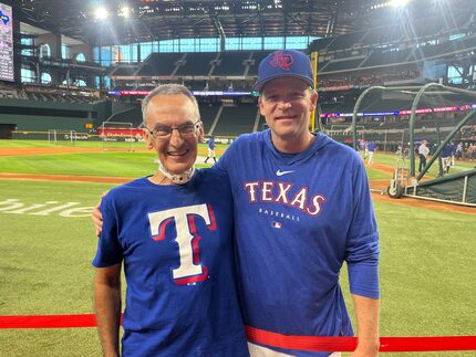 Two men in MLB Texas Rangers t-shirts stand together on the field in a professional baseball...