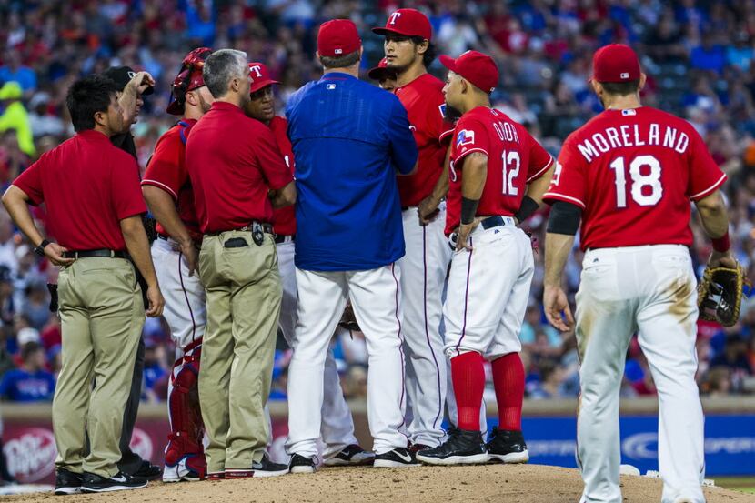 Texas Rangers starting pitcher Yu Darvish (11) talks trainers on the mound during the fifth...