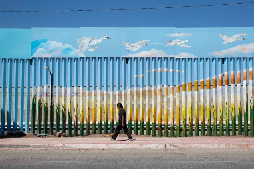 A man walks past the painted border fence in Agua Prieta, Mexico across the border from...
