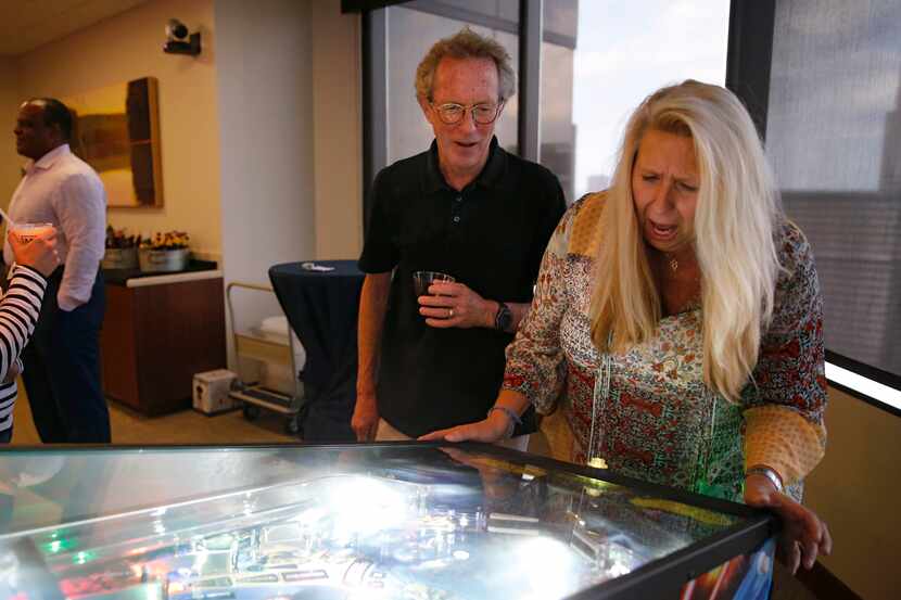 Sharon Blackstock plays a game of pinball while Rick Addison watches her lose the ball...