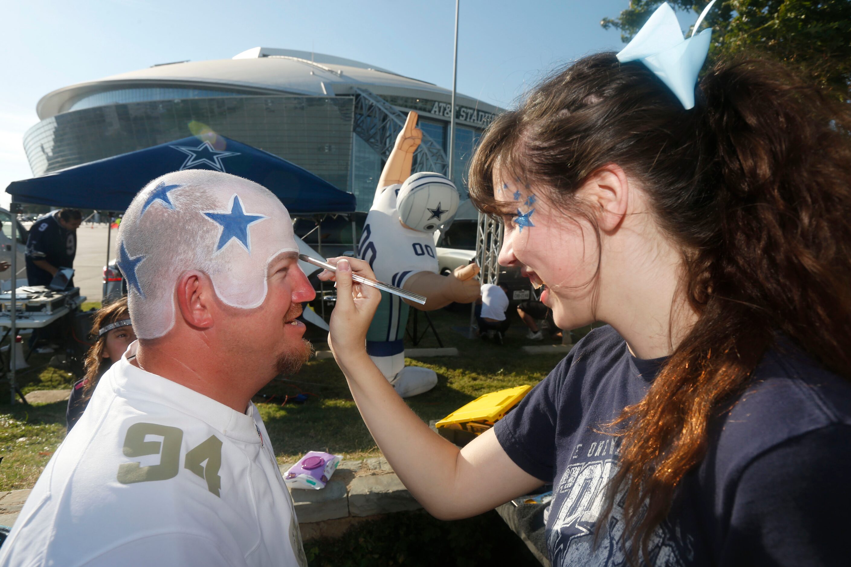 Jerry Blevins of Austin gets a helmet painted on this head by Lydia Parris, of Kitty &...