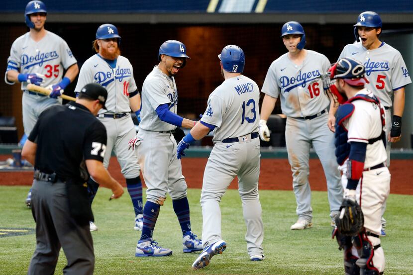 Los Angeles Dodgers first baseman Max Muncy (13) is welcomed to home plate by his teammates...