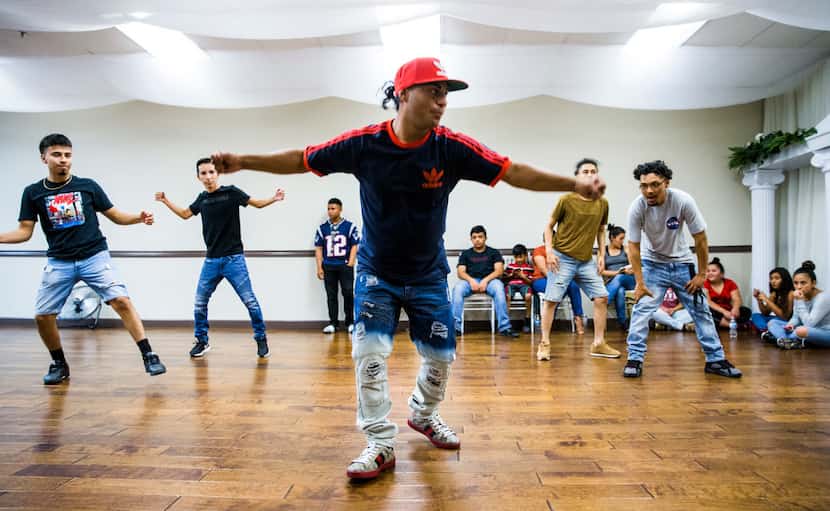 Lucky Franco (center) teaches the Latin Boyz Cadets dancers some new moves during a...