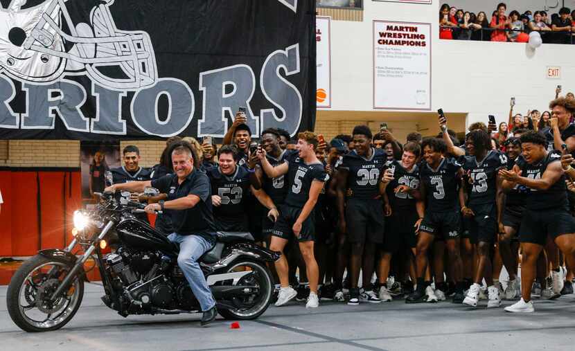 Martin High School head football coach Bob Wager rides his motorcycle past the football team...