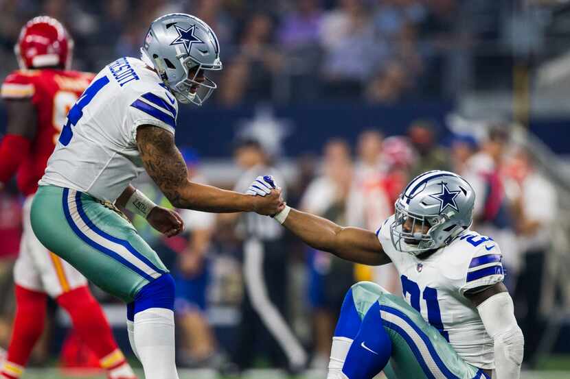 Dallas Cowboys quarterback Dak Prescott (4) helps running back Ezekiel Elliott (21) up after...