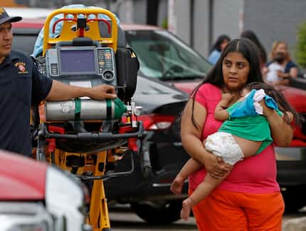  Victims of a four-alarm fire walk to an awaiting ambulance with a Dallas Fire-Rescue...