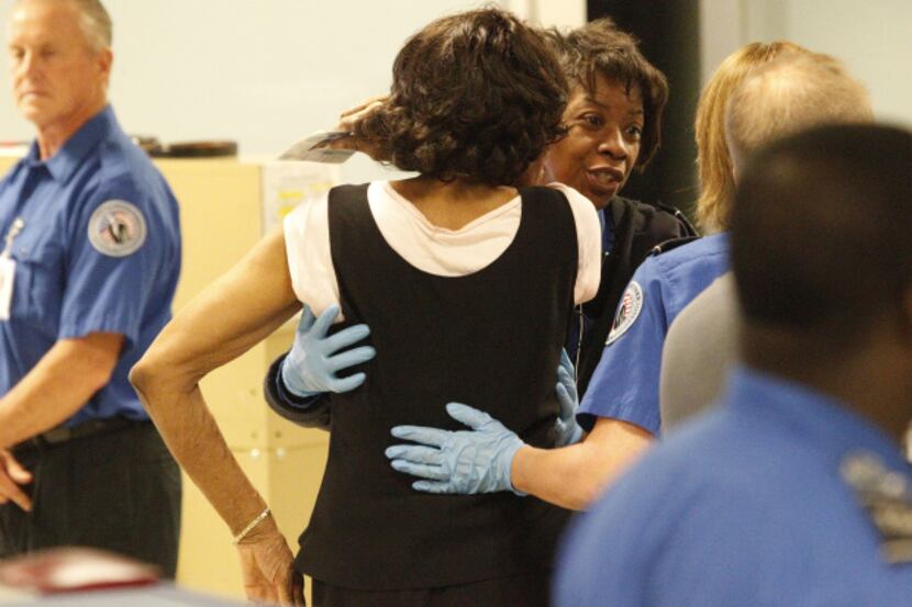 TSA inspectors check an airline passenger at a security checkpoint at Dallas-Fort Worth...