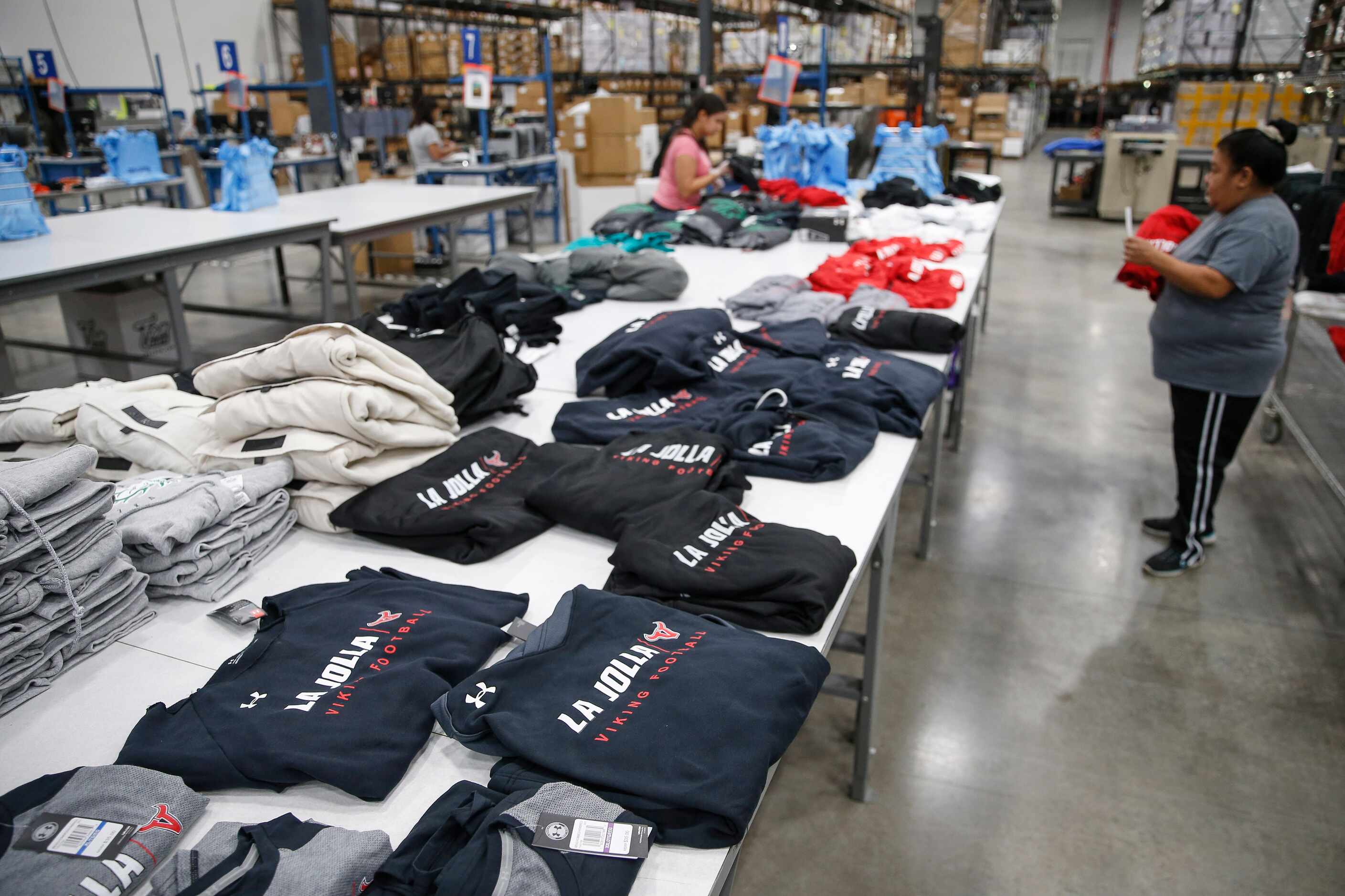 Workers fulfill custom design apparel orders at BSN Sports. The factory in Grand Prairie is...