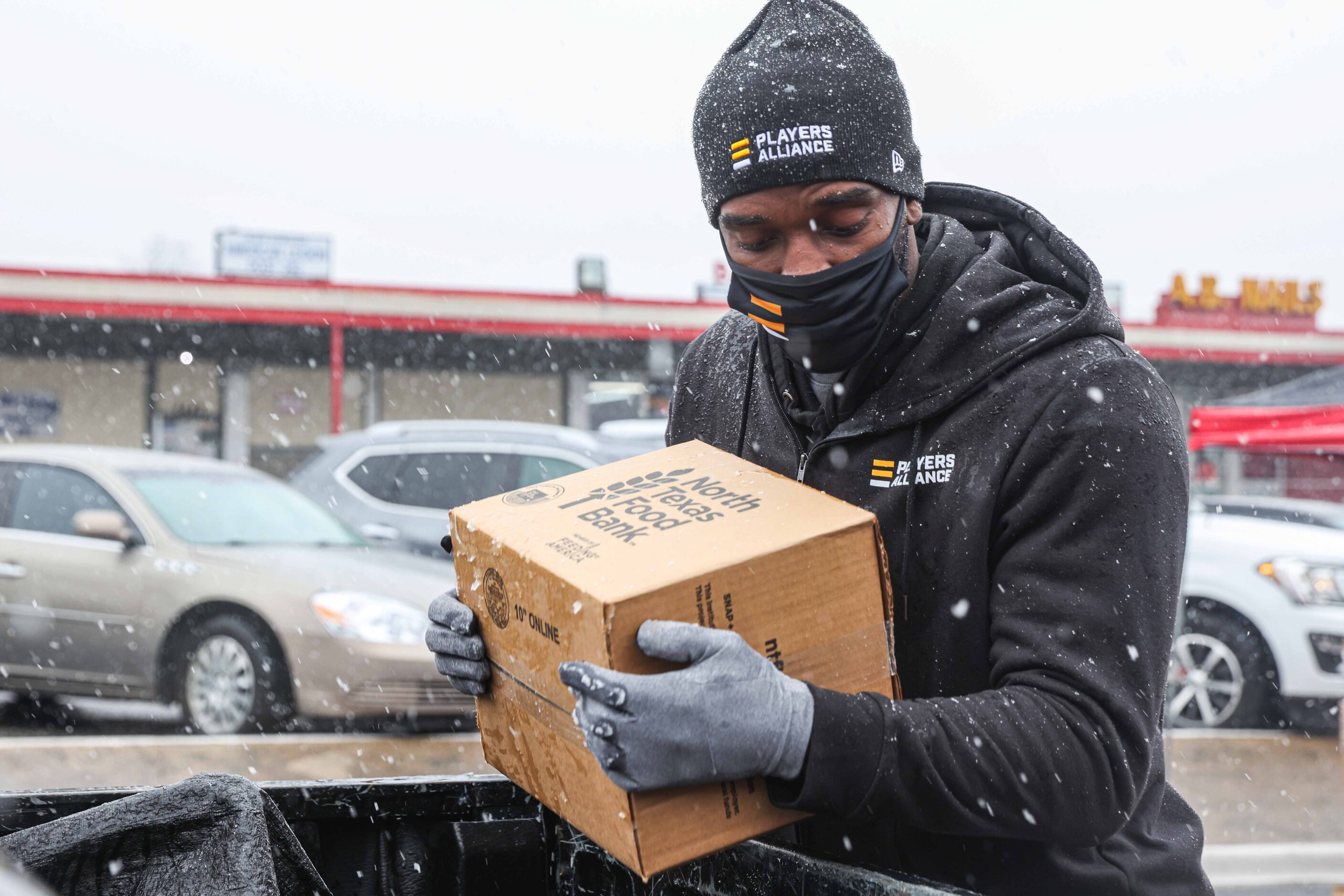 Rangers pitcher Taylor Hearn, places a box of food in the truck of a car as part of the...