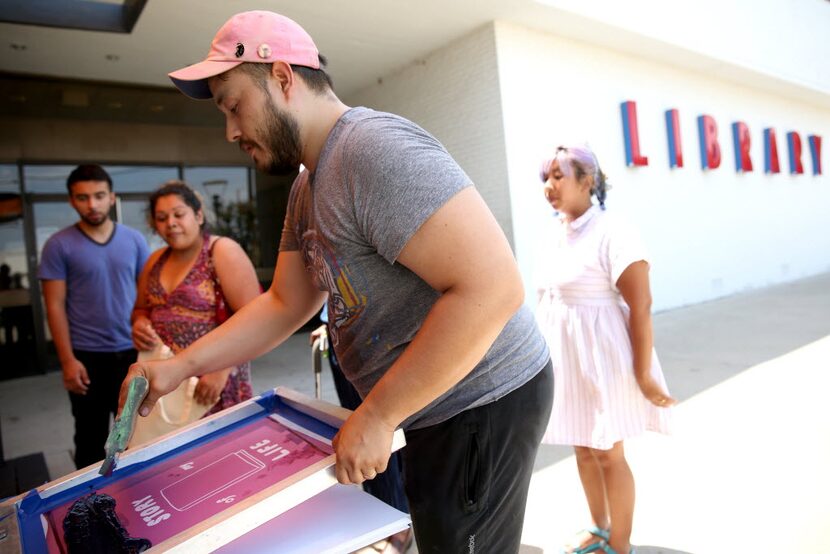 Artist Taro Waggoner demonstrates silk screen printing during a pop-up art event hosted by...