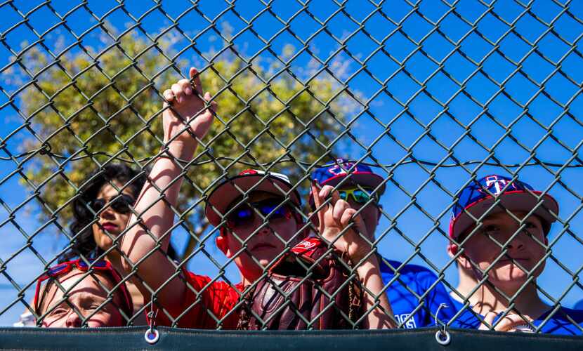 Texas Rangers fans watch batting practice during a workout at the team's spring training...