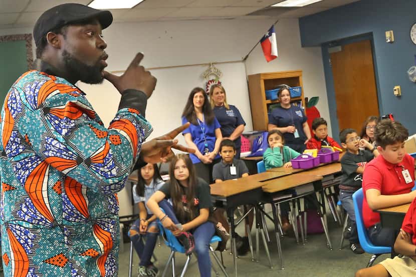 Antoine Dinka, who as a youngster attended Britain Elementary, signs to students as he tells...