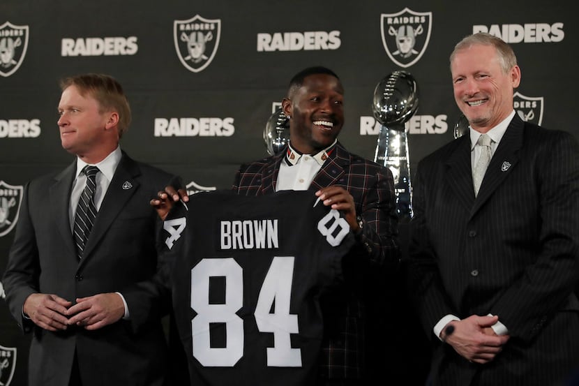 Oakland Raiders wide receiver Antonio Brown, center, holds his jersey beside coach Jon...