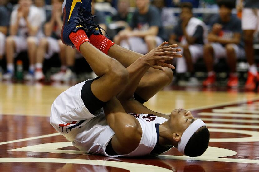 Justin Northwest's Avery Anderson (3) rolls after colliding under the basket during the...