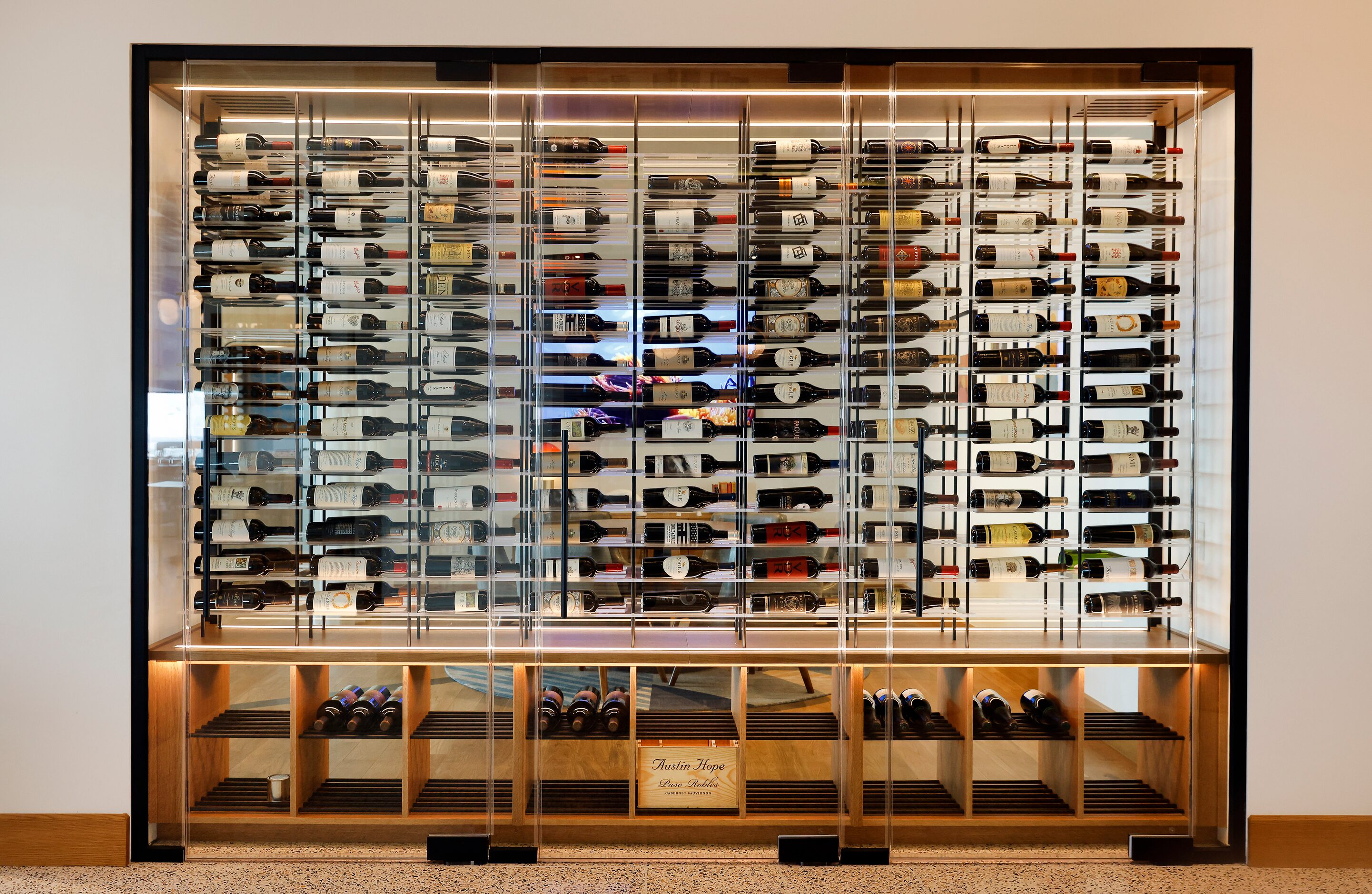 A large, see through wine rack is viewed inside the restyled mid-century modern...