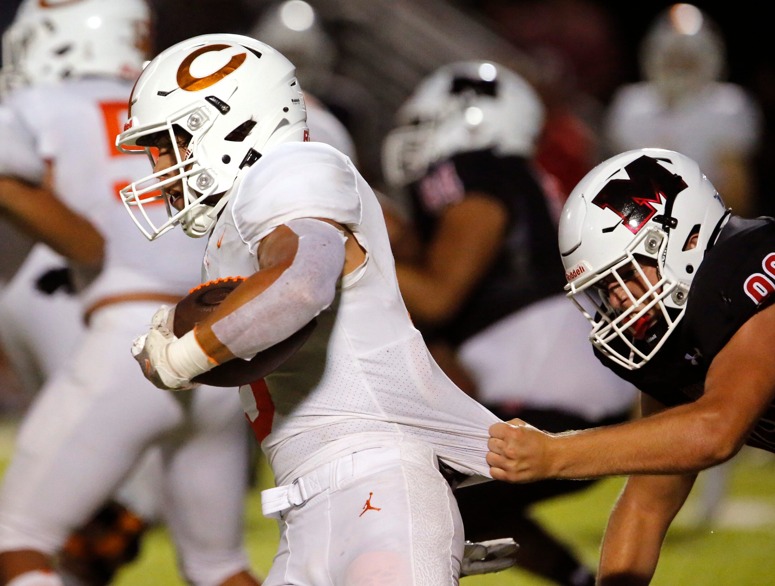 Melissa High School defensive lineman Dylan Smith (99) tries to hang onto the jersey of...