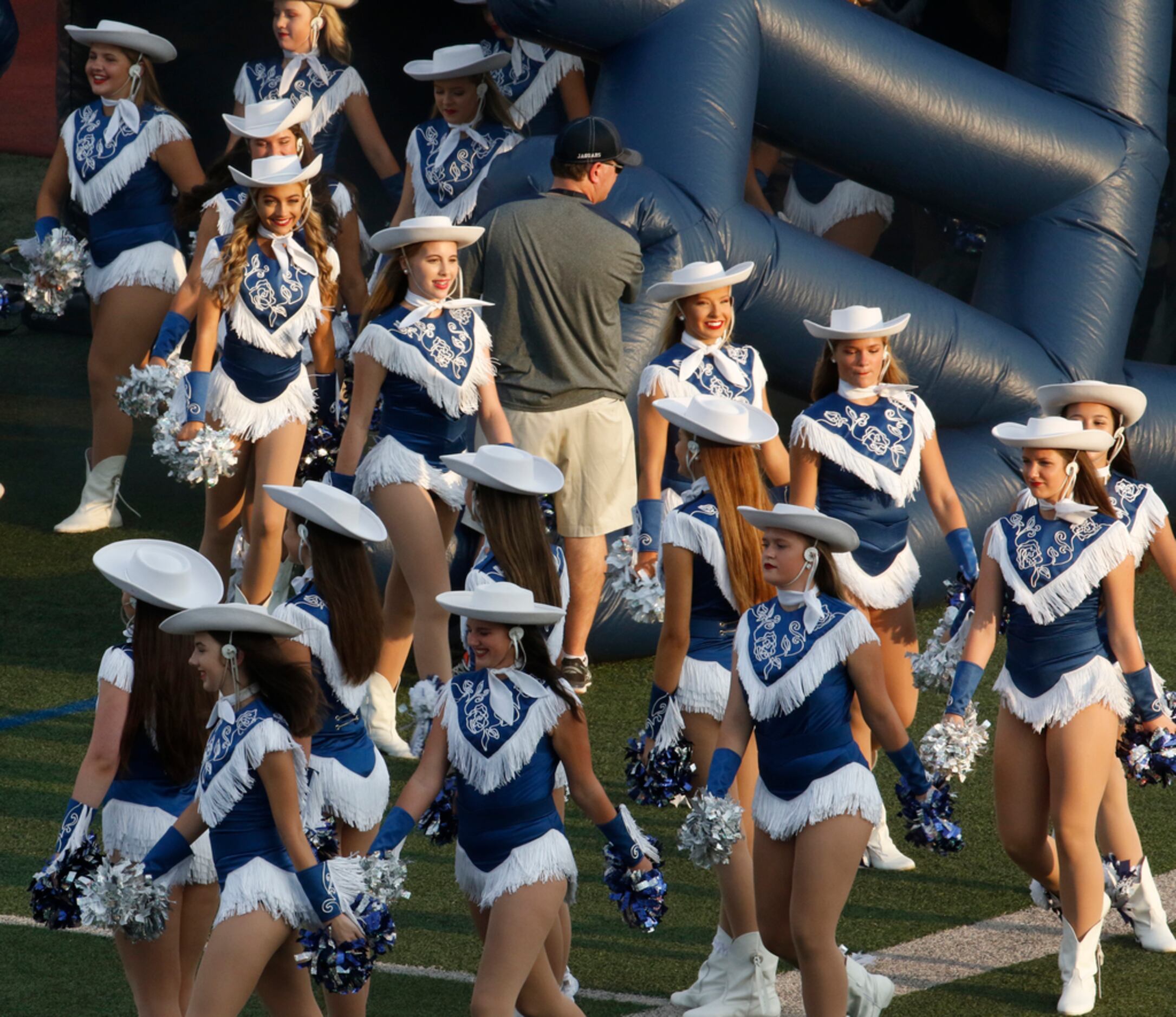 Members of the Flower Mound drill team emerge onto the field through an inflatable helmet...