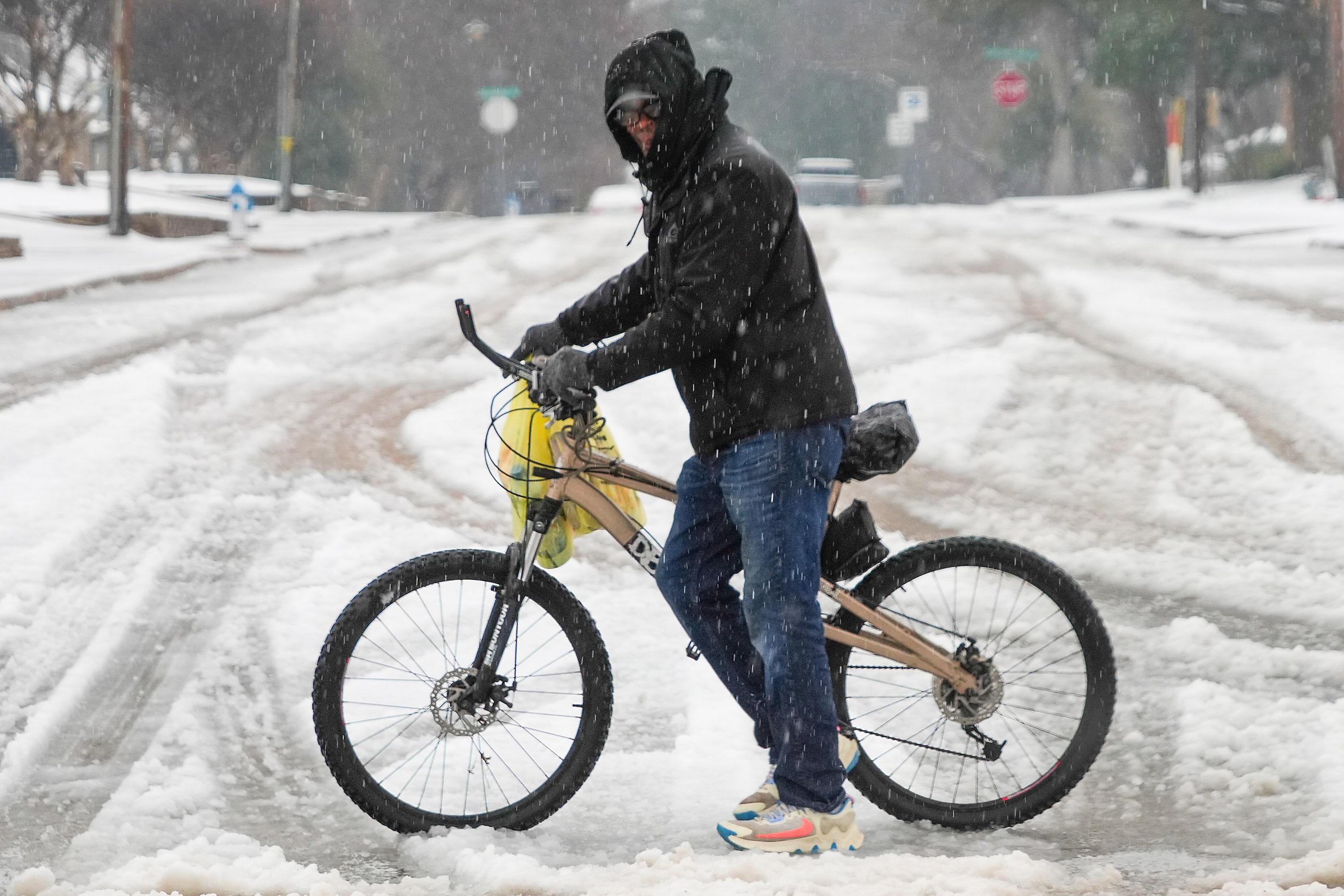 A man pushes his bicycle through heavy slush as snow falls on Thursday, Jan. 9, 2025, in Plano.