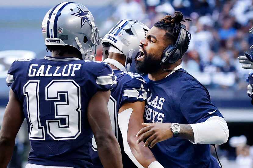 Injured Dallas Cowboys running back Ezekiel Elliott (right) chest bumps fellow running back...