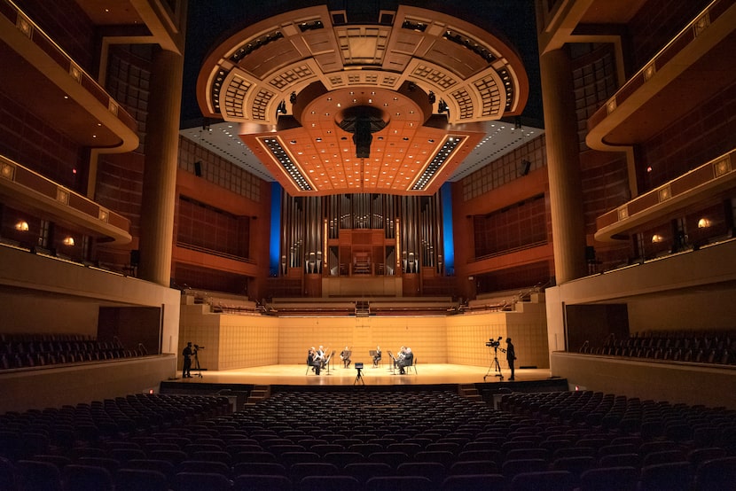 Camera operators, far-left and far-right, record the Dallas Symphony Orchestra as they...