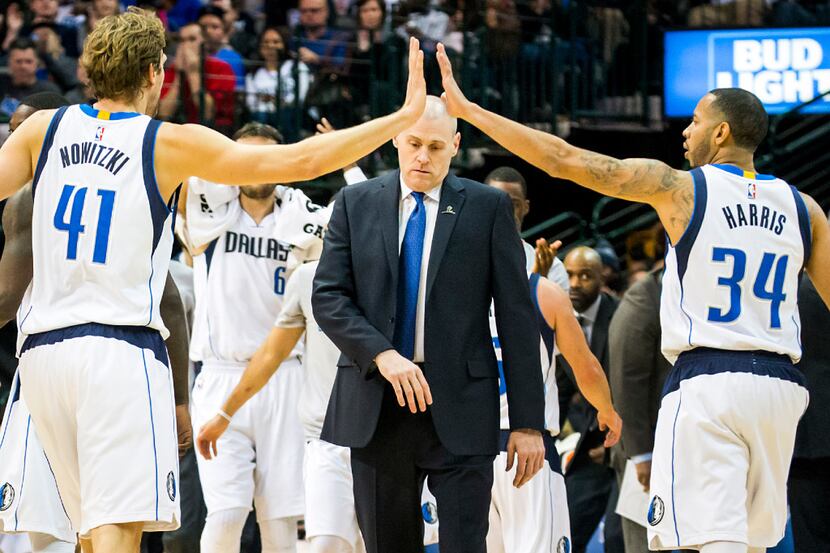 Dallas Mavericks head coach Rick Carlisle gets caught in the middle of a high five between...