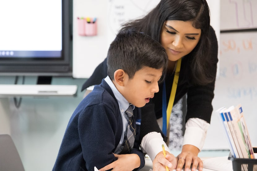 teacher helping student in classroom