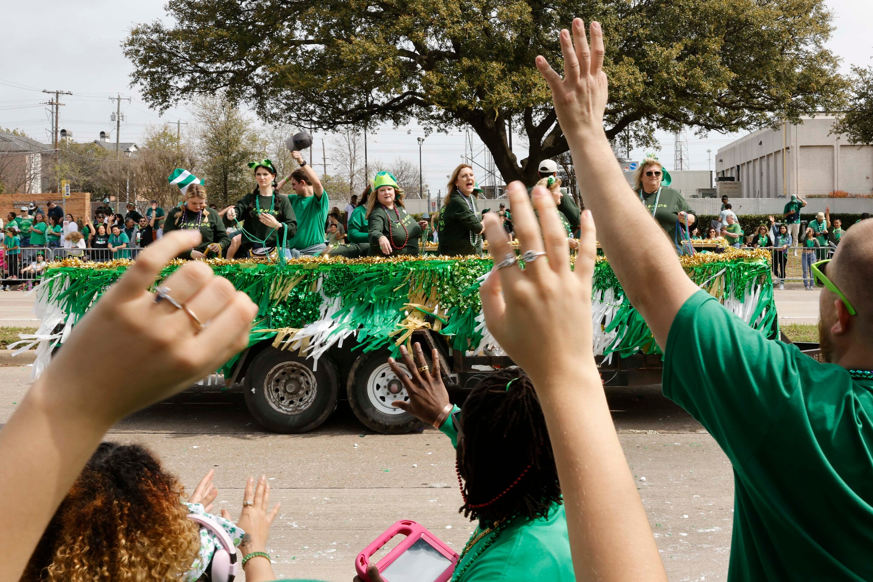 Attending crowd tries to catch green bead necklaces tossed by marchers during a Saint...