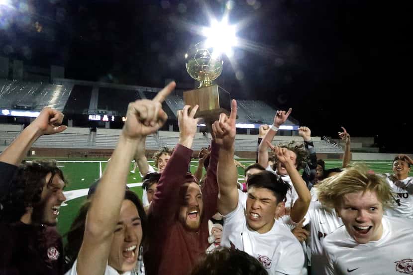 Plano High School Head Coach Tex McCullough holds up the quarterfinal trophy after winning...