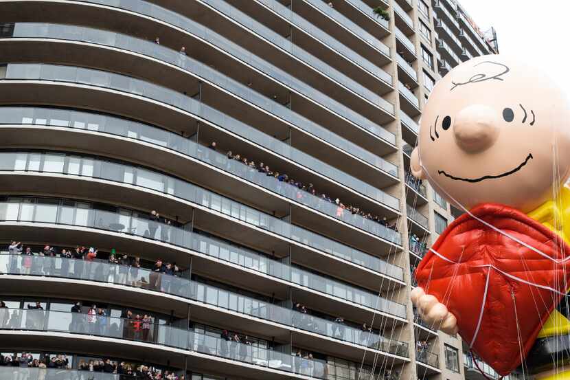 People watch from a nearby building as the Charlie Brown balloon passed by during the 90th...