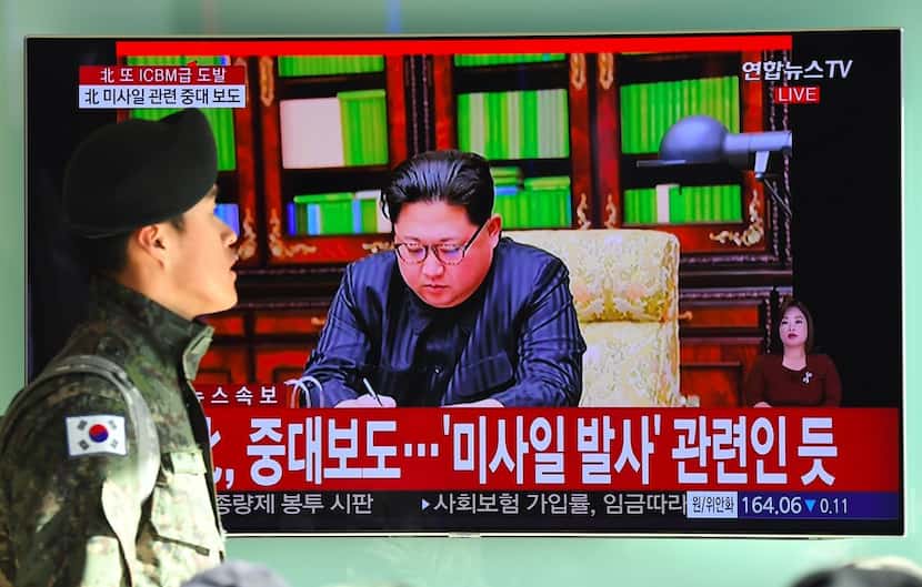 A South Korean soldier walks past a television news screen showing North Korean leader Kim...
