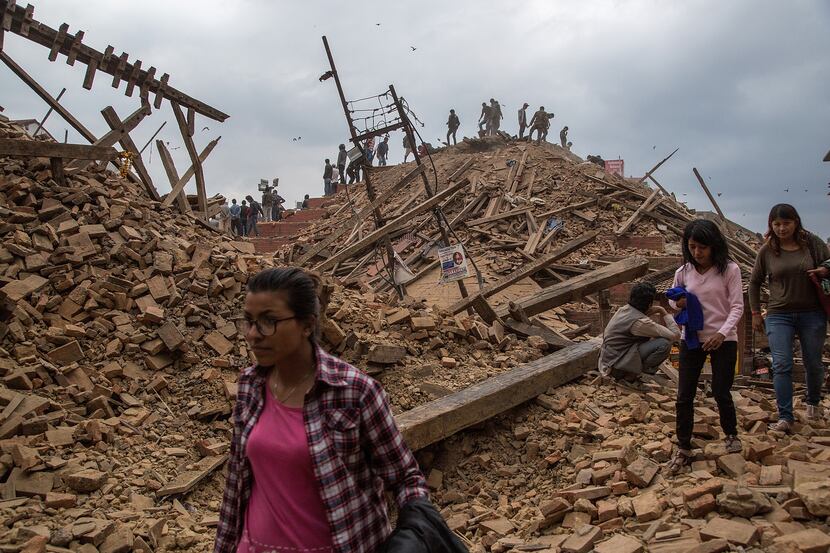 KATHMANDU, NEPAL - APRIL 25: People stand on top of debris from a collapsed building at...