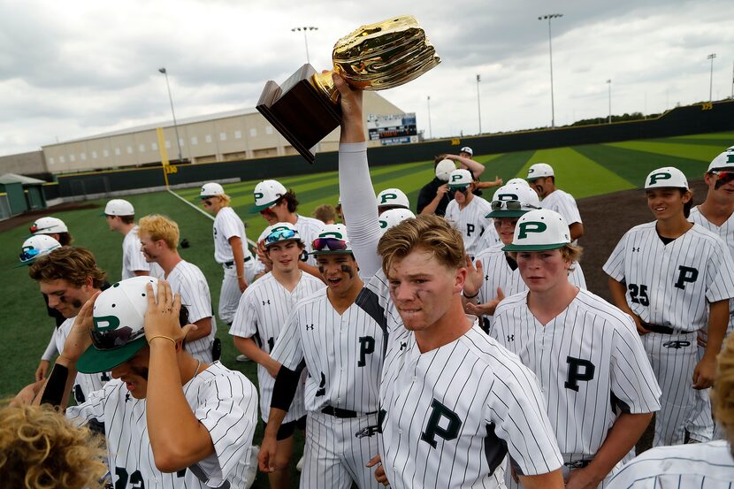 Prosper catcher Easton Carmichael (11) hoists up the area trophy after his team’s victory as...