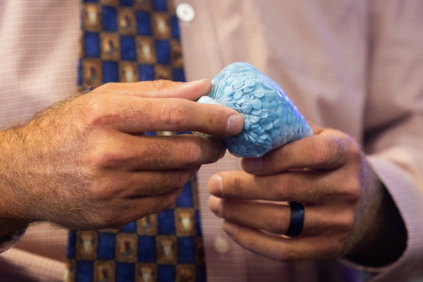 Fort Worth Police Sgt. Scott Banes holds a bag of demonstrative pills bearing the appearance...