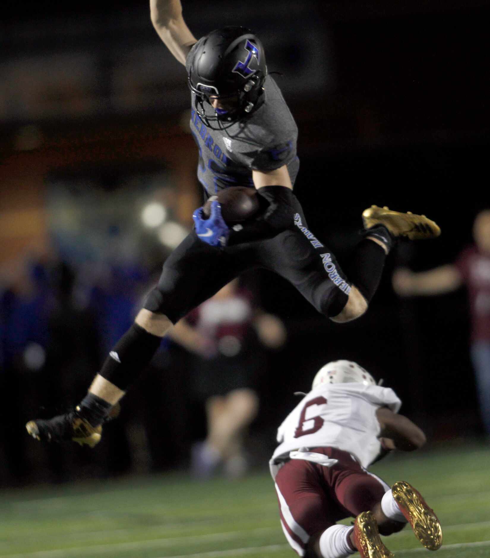 Hebron running back Lane Haworth (22) leaps over the attempted tackle of Plano defensive...