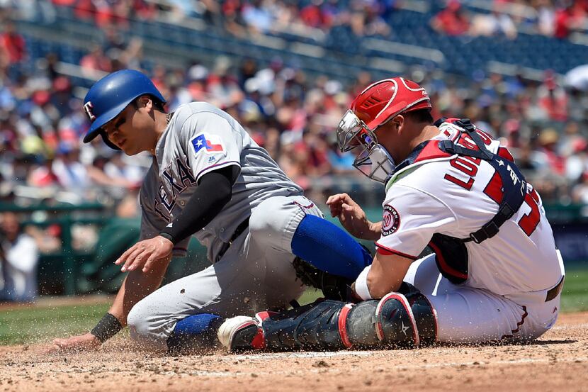 Texas Rangers' Shin-Soo Choo, left, is out at home by Washington Nationals catcher Jose...