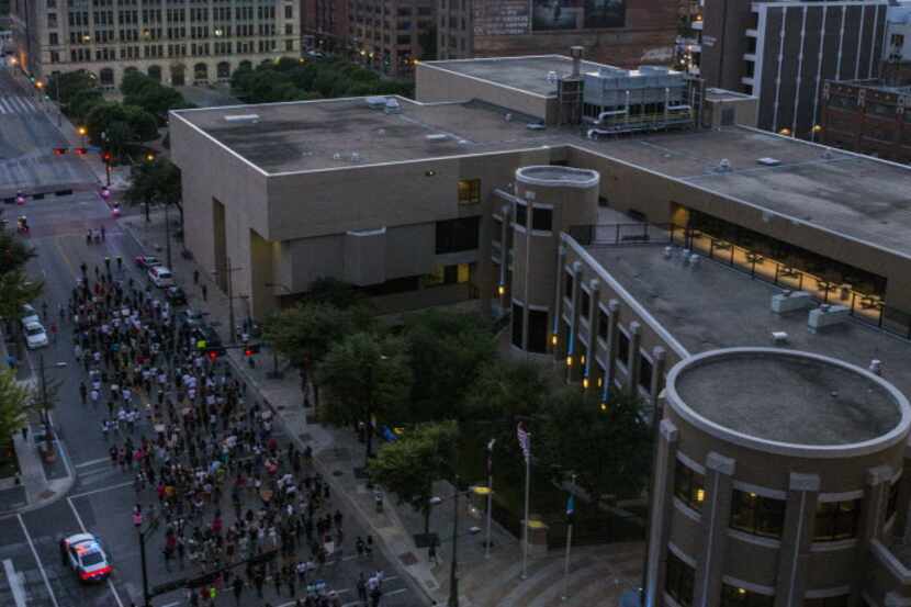 Protestors march west on Main St past El Centro College (right) before gunmen shot 11 people...