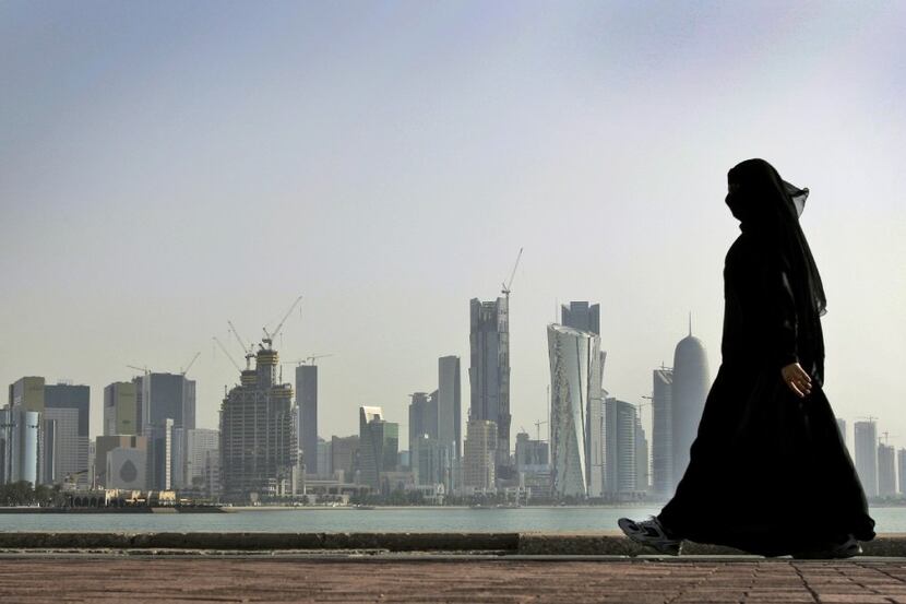 FILE - In this May 14, 2010 file photo, a Qatari woman walks in front of the city skyline in...