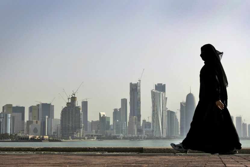 Una mujer qatarí camina frente a la ciudad de Doha.
