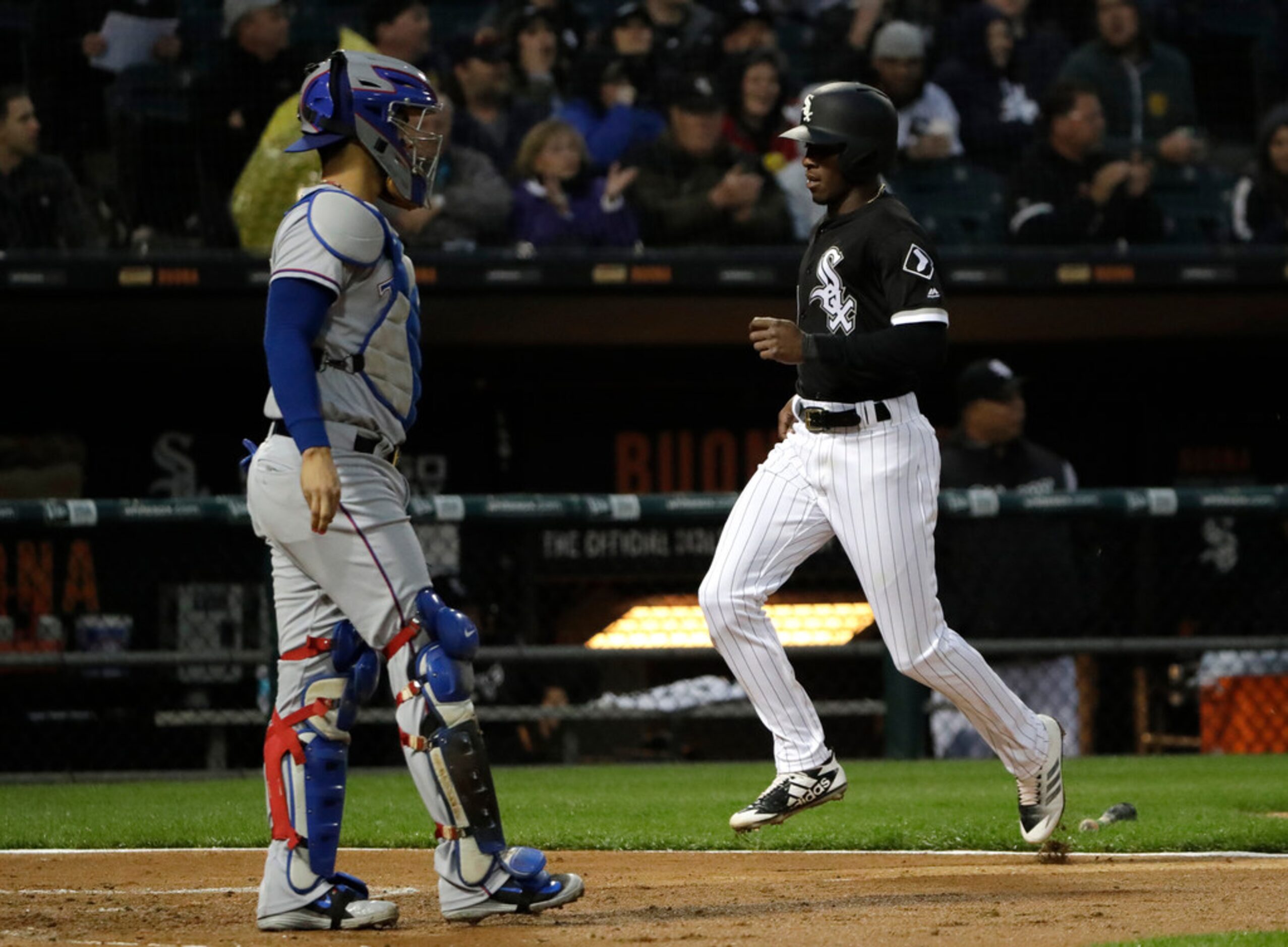 Chicago White Sox's Tim Anderson, right, scores as Texas Rangers catcher Robinson Chirinos...